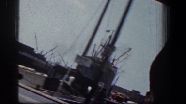 1961: large ships remaining anchored in the wharf and vehicles are moving