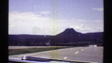 1969: car on highway driving towards a mountain ARIZONA