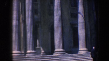 1962: a man walking in front of a large building with ionian columns