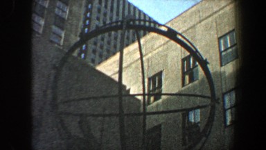 1960: people walking in opposite directions before a sculpture depicting a man