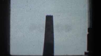 1961: a tall black tower high up in the air in the city with many buildings