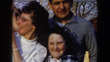 1961: a family of three enjoying time outside with a orange tabby kitten playing