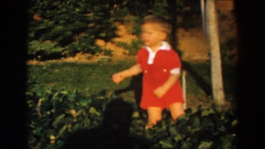 1962: little boy plays with dad and other kids in the grass GLENDALE, CALIFORNIA