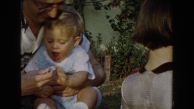 1962: father feeding the beautiful kid on his lap with a spoon GLENDALE