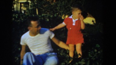 1962: child sucking his thumb and man with glasses sitting in grass