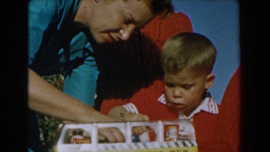 1962: family gathering on a birthday as little boy learns to play with his toys.