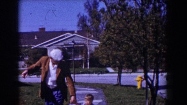1962: man in white beret and brown jacket walking child across yard GLENDALE
