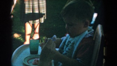 1962: woman feeds toddler with spoon and woman holds birthday cake with three