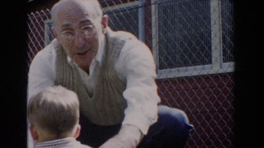 1962: a man wearing a sweater vest holding a baby wearing a vest GLENDALE