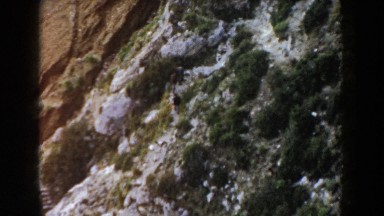 1960: several people walking along a trail in a rocky area with lots of trees.