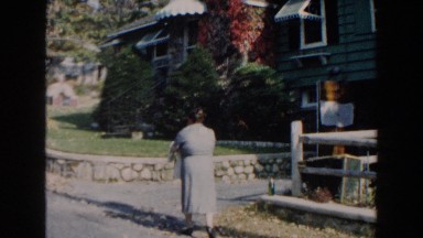 1960: a fat old lady with bag nearing a beautiful buildings with frontage MIAMI