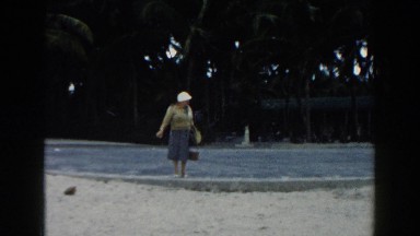 1960: grandmother enjoys beachcombing during family vacation to island paradise.