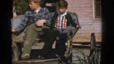 1961: three boys are visiting a farm with antique equipment and a woodpile