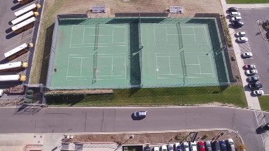 an aerial view of four newly completed tennis courts surrounded by dry grass.