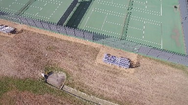 birds eye view of 4 full-size tennis courts adjoining a nearby school yard.