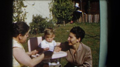 1958: two middle-aged women are helping a little boy eat cake