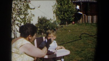 1958: mother feeding her son outside in his highchair. CALIFORNIA