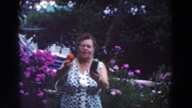 1964: Older Woman Gardening with Tomato and Cucumber in Tustin Wisconsin
