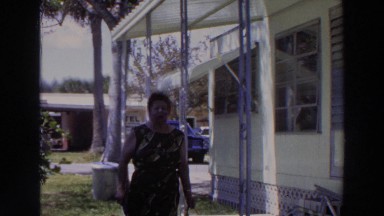 1966: person standing outside a structure talking and smiling