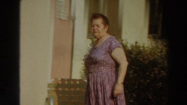 1966: a woman wearing a purple dress walking outside a building PUERTO RICO