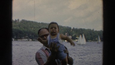 1966: man holds toddler in front of him with both hands