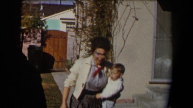 1958: mother with her child outside hanging laundry on clothing line and excited