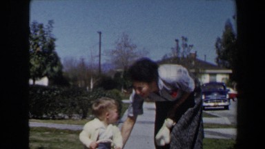 1958: mother helping her son ride his toy car on the sidewalk. LAS VEGAS