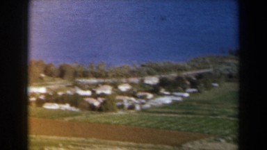 1960: aerial view of waterfront town, scenic plane exploring mountains