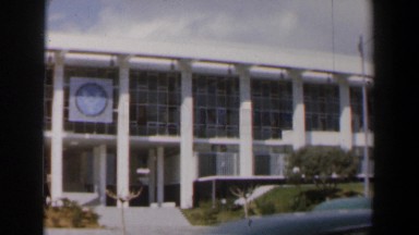1960: building on the side of the road with many windows and vehicles driving