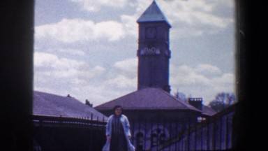 1960: a lady standing on a low brick wall in front of a clock tower BALTIMORE