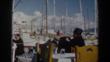 1960: An Older Couple Dine Outside Among Sailboats in Israel