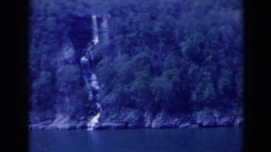 1963: cliff face showing waterfall, plants, and the coast line NIAGARA FALLS