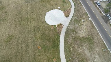 a cement path in a large green field next to a road COLORADO