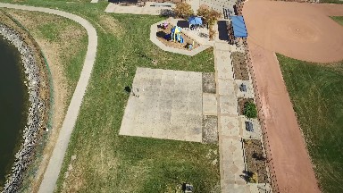 aerial drone hovers over a park, capturing a sky view of a basketball court and