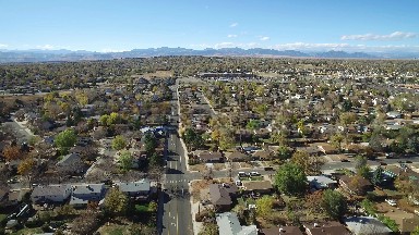 the aerial view of a large town with many buildings, roads, greenery etc.