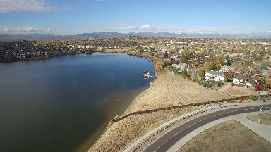 a road that runs next to a large body of water with houses lining the roadway