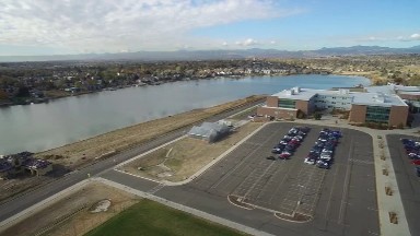 aerial view of a city around a lake with many buildings, courts, vehicles, etc.
