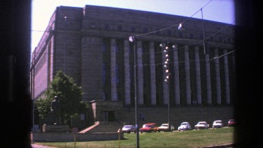 1975: large building in city with colorful cars in front of it SWEDEN