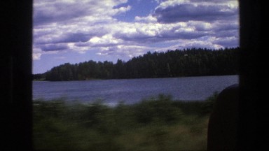 1975: Driving Along the Shoreline with a View of the Lake and Forest, Sweden