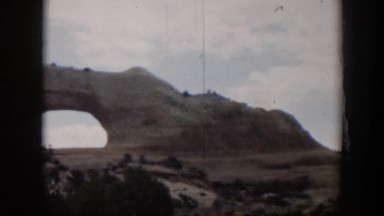 1951: Arched Rock with Bushes on a Clear Day in Utah