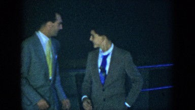 1952: two men in formal dress walking and talking on the balcony of the house