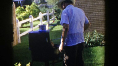 1953: man grilling on a sunny day in the backyard of his home LUBBOCK TEXAS