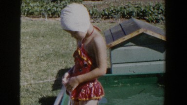 1953: kid enjoying the warm temperatures outside while in a swimsuit