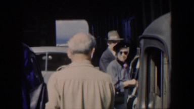 1951: An Older Couple Stand Next to Their Car on a Sunny Day in Cuba