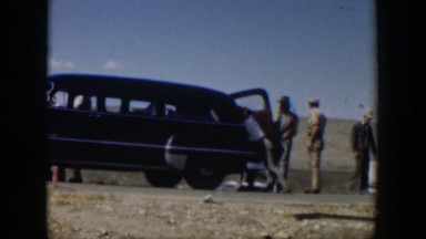 1951: men standing out by a car wreck, working on their own vehicle. TEXAS