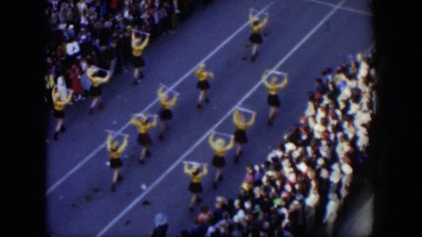 1951: women hold and swing batons in formation during a parade