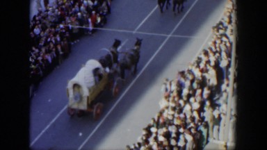1951: ceremonial parade with horse pulling carts progressing amid larger