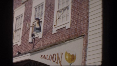 1954: mannequin waving from window in historic western town at silver saloon.