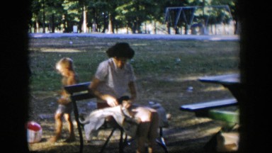 1954: Woman Sitting Outside Fixing Clothes, Nevada