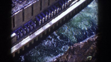 1954: Aerial View of a Dam with Raging Water Running Between Massive Rocks